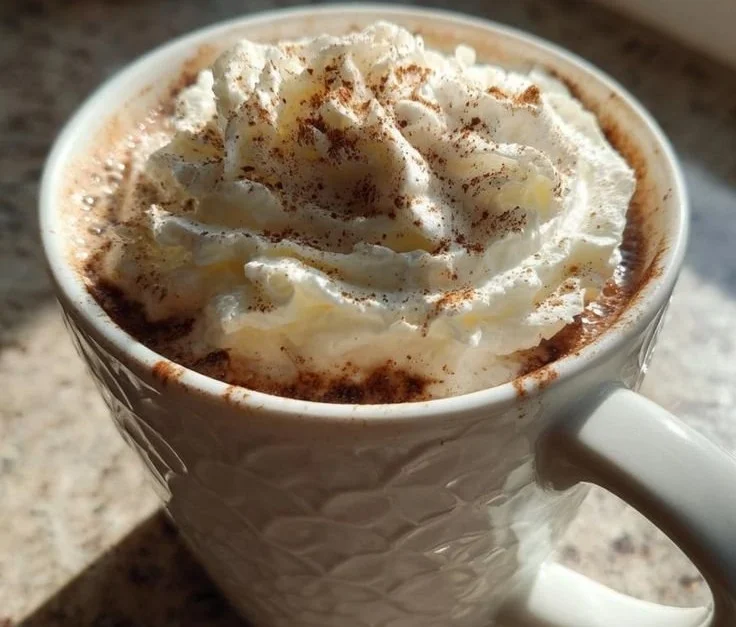 A cozy mug of Christmas Coffee with festive decorations in the background.